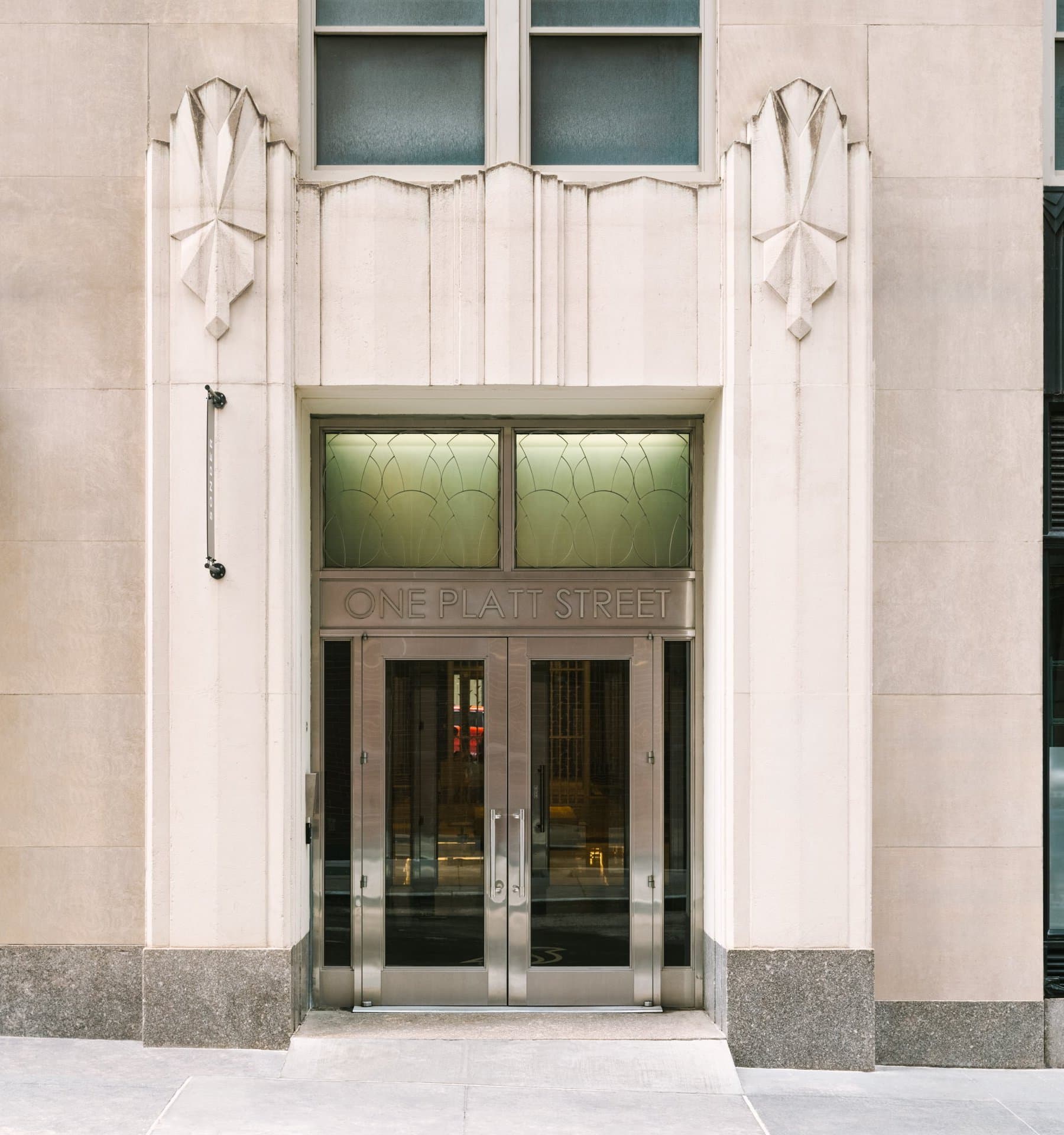 Art Deco limestone entrance of One Platt Street, with metal double doors under a One Platt Street transom